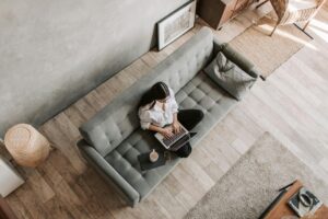 An overhead photograph of a woman sitting cross legged on a couch with a laptop. This is to illustrate the article 3 ways freelancers can build trust with clients